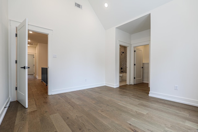 empty room featuring high vaulted ceiling and light hardwood / wood-style flooring