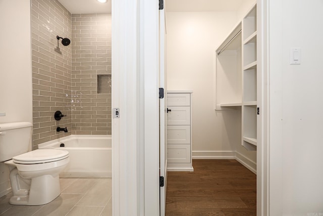 bathroom featuring tiled shower / bath combo, hardwood / wood-style flooring, and toilet