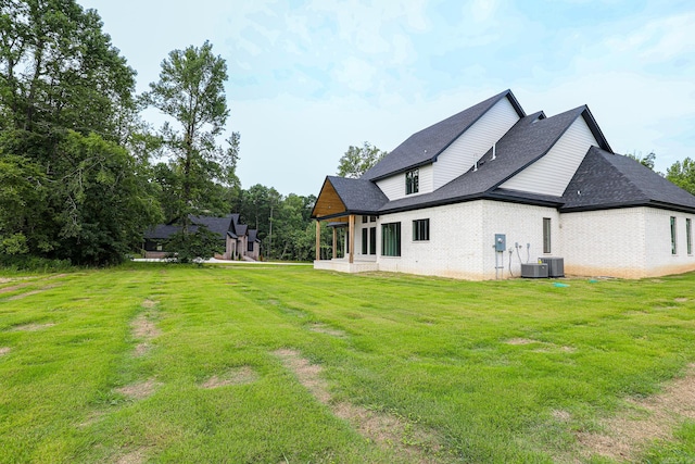 back of house featuring central air condition unit and a yard