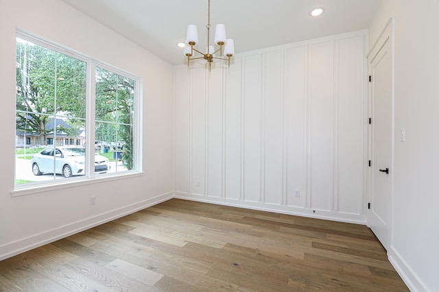 unfurnished room with hardwood / wood-style floors and an inviting chandelier