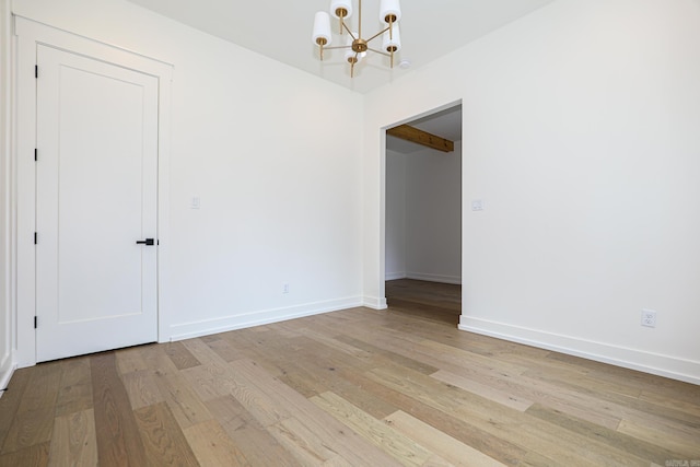 spare room with light hardwood / wood-style floors and a notable chandelier