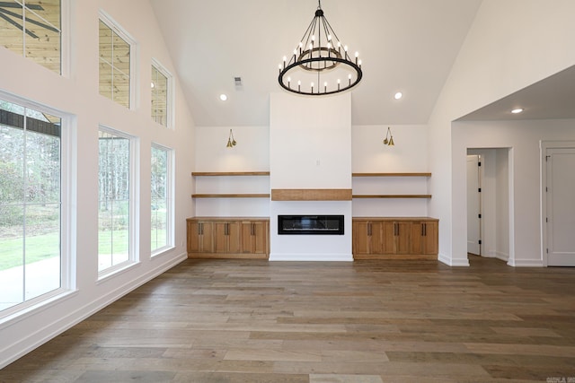 unfurnished living room featuring high vaulted ceiling, wood-type flooring, and a notable chandelier