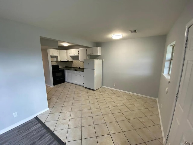 kitchen with white fridge, black range with electric stovetop, white cabinetry, and light tile patterned flooring