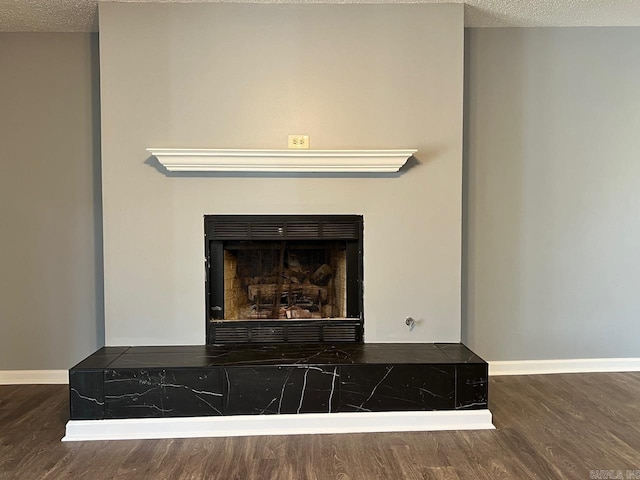 room details with hardwood / wood-style flooring, a textured ceiling, and a tile fireplace