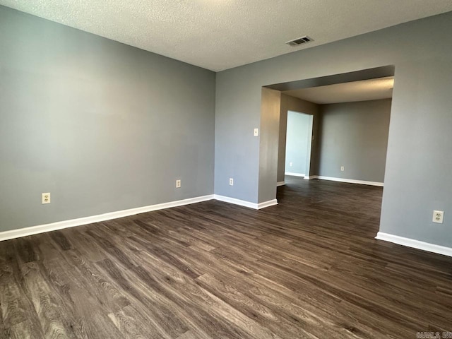 unfurnished room with a textured ceiling and dark hardwood / wood-style flooring