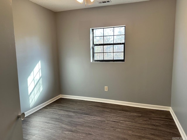 spare room featuring dark hardwood / wood-style floors, ceiling fan, and a textured ceiling