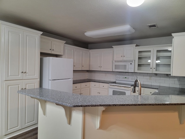 kitchen featuring white cabinets, dark hardwood / wood-style flooring, white appliances, and a breakfast bar area