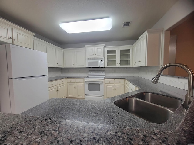 kitchen featuring decorative backsplash, white appliances, sink, and dark stone counters