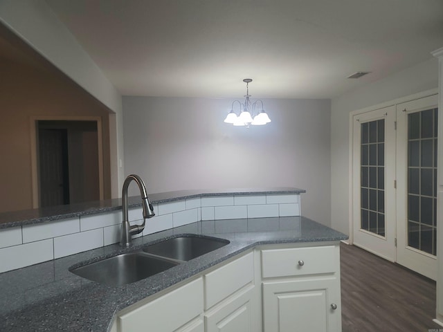 kitchen with pendant lighting, white cabinets, sink, dark hardwood / wood-style floors, and a notable chandelier