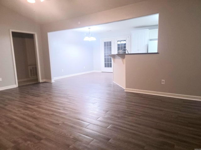 unfurnished living room with french doors, dark hardwood / wood-style flooring, lofted ceiling, and a notable chandelier