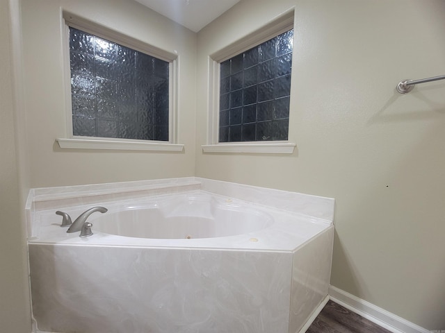 bathroom with hardwood / wood-style floors and a bath