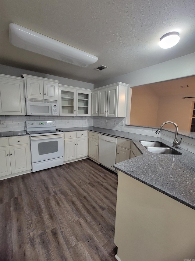 kitchen with white cabinetry, sink, dark wood-type flooring, backsplash, and white appliances