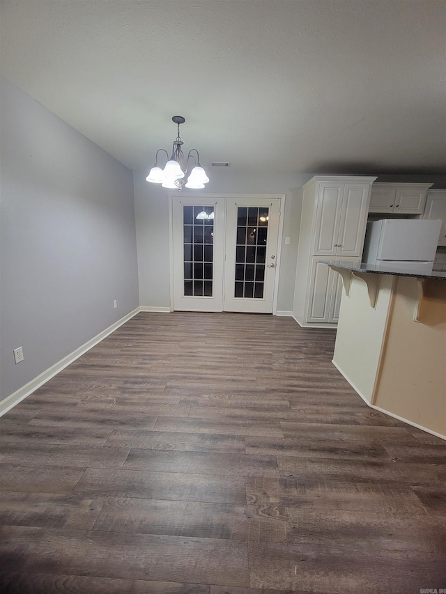 unfurnished dining area featuring a chandelier and dark hardwood / wood-style floors