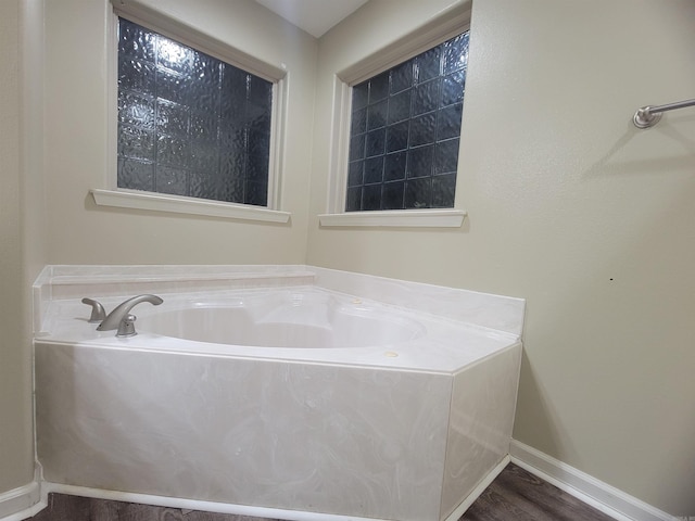 bathroom with a bathing tub and hardwood / wood-style flooring