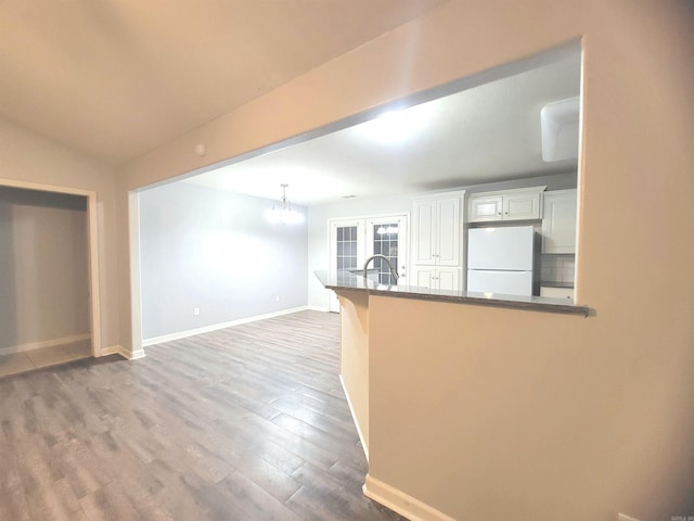 kitchen with french doors, white cabinets, hardwood / wood-style flooring, white fridge, and kitchen peninsula