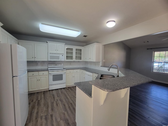 kitchen featuring kitchen peninsula, a kitchen bar, white appliances, sink, and white cabinetry