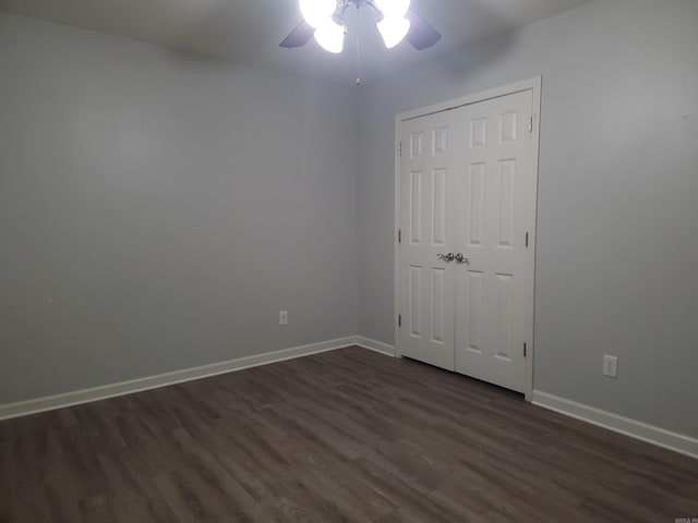 unfurnished bedroom with ceiling fan, dark wood-type flooring, and a closet