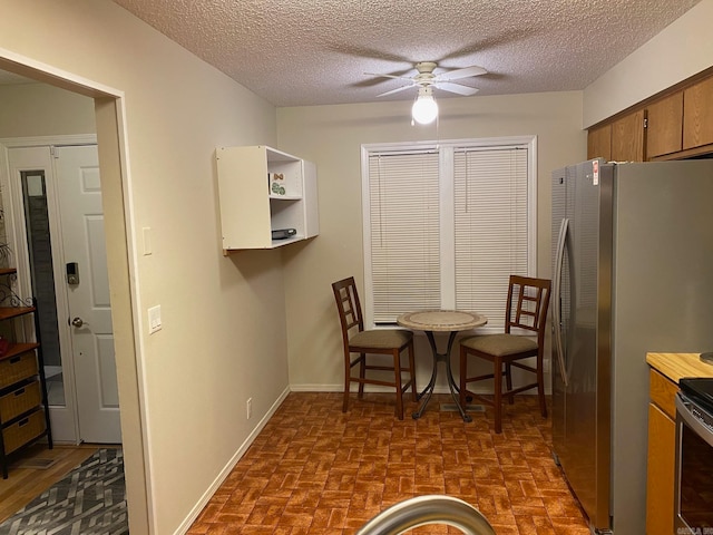 kitchen with ceiling fan, a textured ceiling, and stainless steel refrigerator