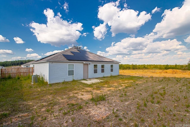 back of property featuring central AC unit and solar panels