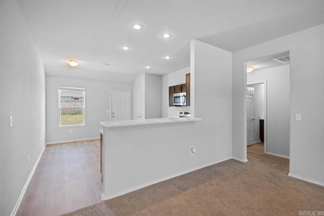 kitchen featuring kitchen peninsula and light colored carpet