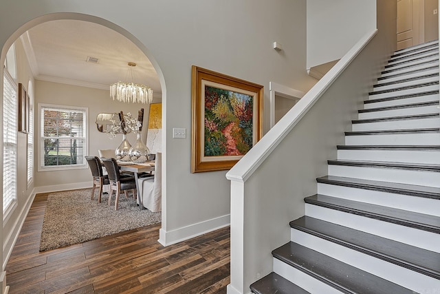 stairs featuring hardwood / wood-style floors, a notable chandelier, and ornamental molding