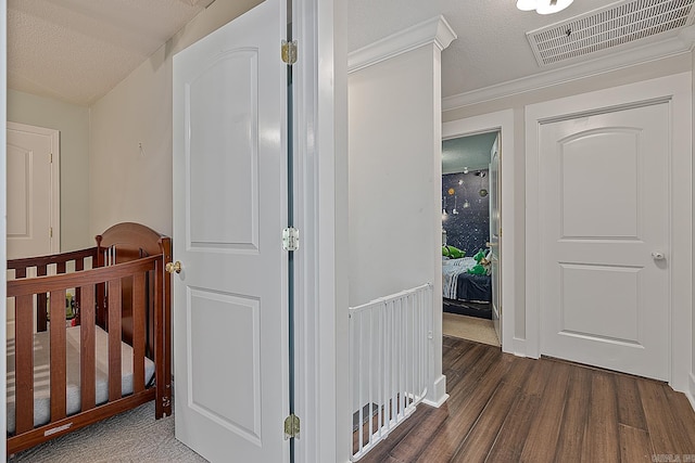 hall with a textured ceiling, dark hardwood / wood-style floors, and crown molding