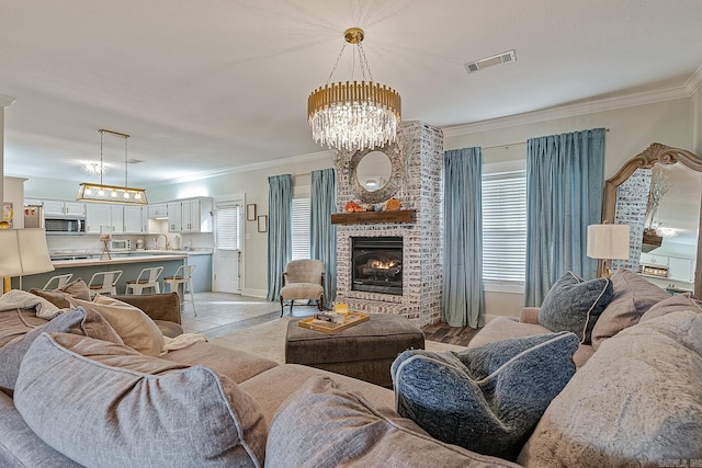 living room with a fireplace, a chandelier, ornamental molding, and sink