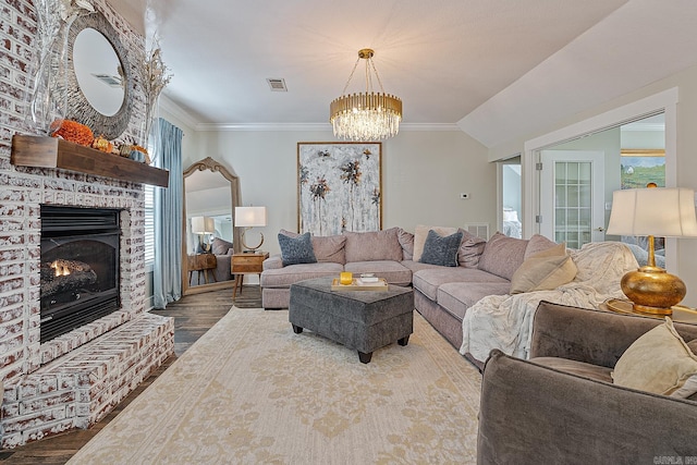 living room featuring wood-type flooring, a brick fireplace, plenty of natural light, and a notable chandelier