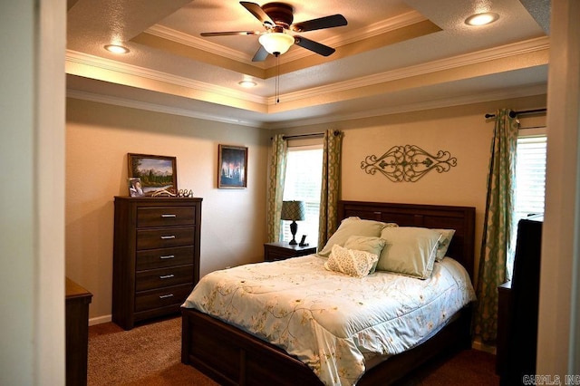 carpeted bedroom featuring a raised ceiling, multiple windows, ornamental molding, and ceiling fan