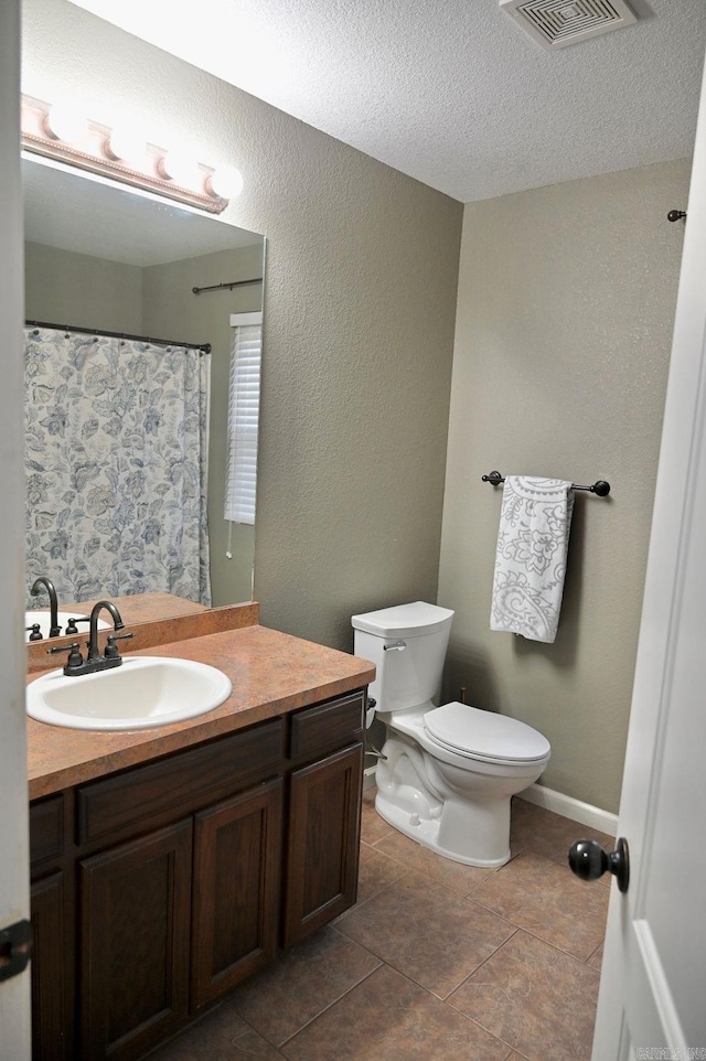 bathroom with tile patterned floors, vanity, toilet, and a textured ceiling