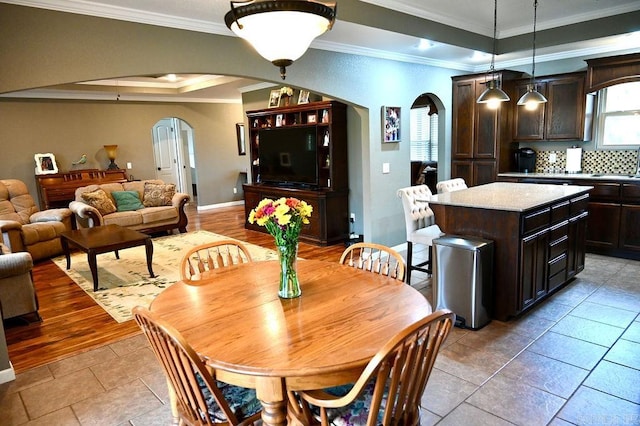 dining area with sink, light wood-type flooring, and ornamental molding