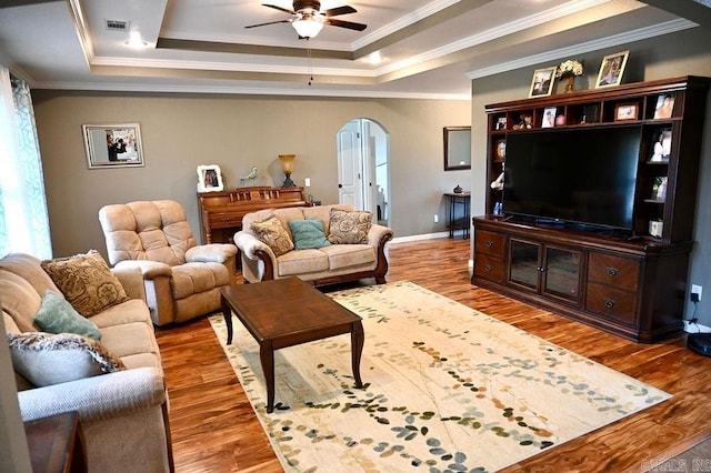 living room with hardwood / wood-style floors, a raised ceiling, and crown molding