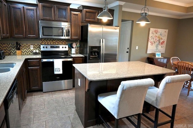 kitchen featuring decorative light fixtures, a kitchen bar, stainless steel appliances, and tasteful backsplash