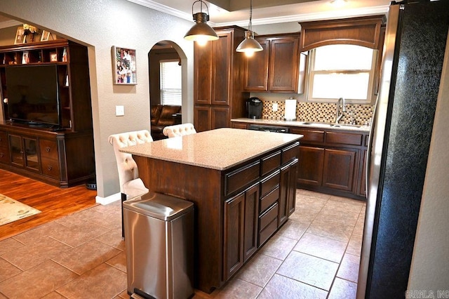 kitchen featuring sink, tasteful backsplash, crown molding, decorative light fixtures, and a kitchen island