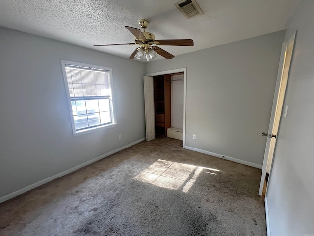 unfurnished bedroom featuring a textured ceiling, ceiling fan, light carpet, and a closet