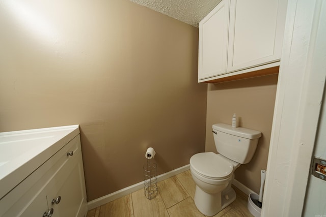 bathroom with toilet, vanity, a textured ceiling, and hardwood / wood-style flooring