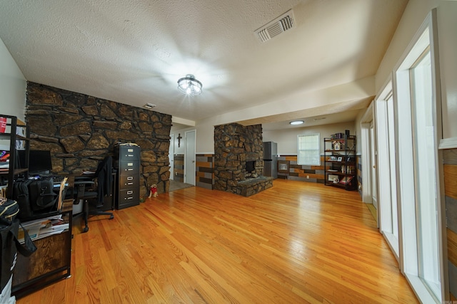 living room with a fireplace, a textured ceiling, and light hardwood / wood-style flooring