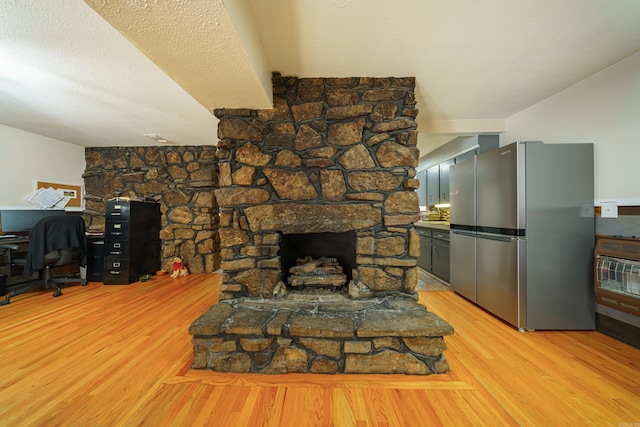 living room featuring a fireplace, a textured ceiling, and light hardwood / wood-style floors