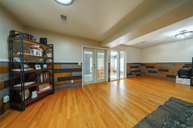 interior space with french doors, a textured ceiling, and light hardwood / wood-style flooring