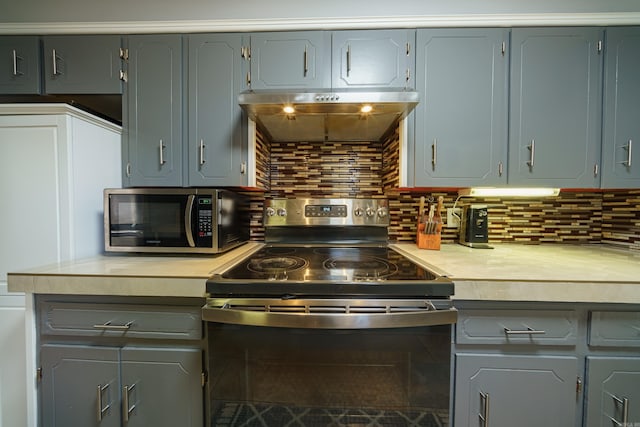 kitchen featuring appliances with stainless steel finishes, gray cabinets, backsplash, and range hood