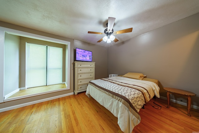 bedroom with ceiling fan, a textured ceiling, and light hardwood / wood-style flooring