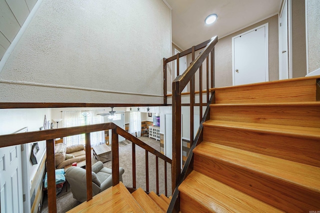 stairs featuring ceiling fan