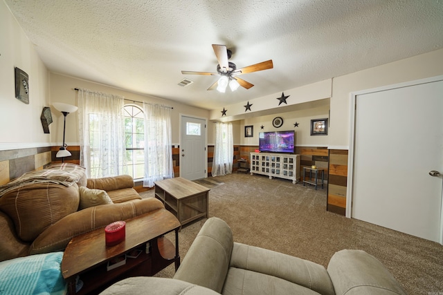 carpeted living room with ceiling fan and a textured ceiling