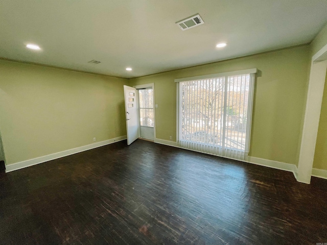 spare room featuring a healthy amount of sunlight and dark hardwood / wood-style floors