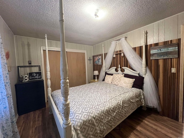 bedroom featuring wood walls, dark hardwood / wood-style flooring, and a textured ceiling