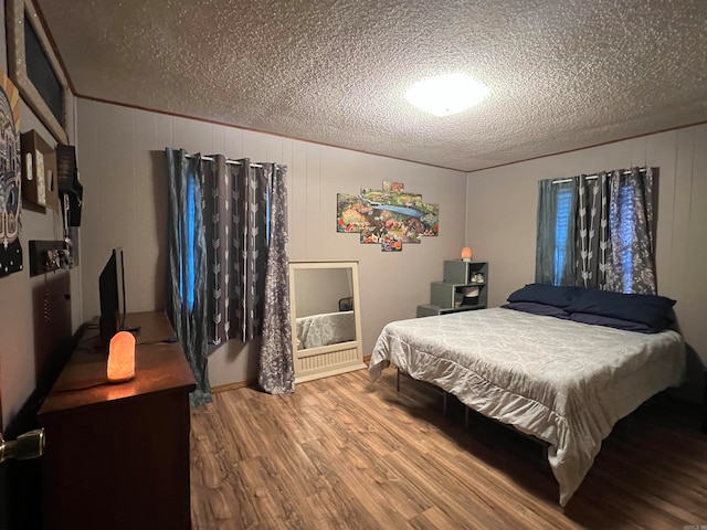 bedroom featuring hardwood / wood-style floors, a textured ceiling, and wooden walls