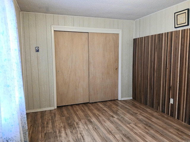 802 Casey St, Leslie, AR 72645 - unfurnished bedroom featuring wooden walls, wood finished floors, a closet, and a textured ceiling