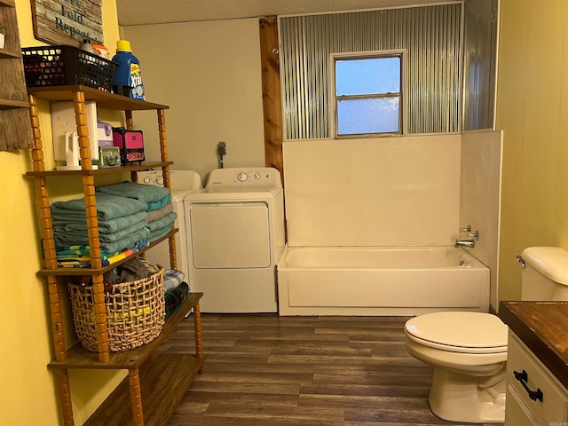 bathroom with separate washer and dryer, a tub to relax in, wood-type flooring, a textured ceiling, and toilet