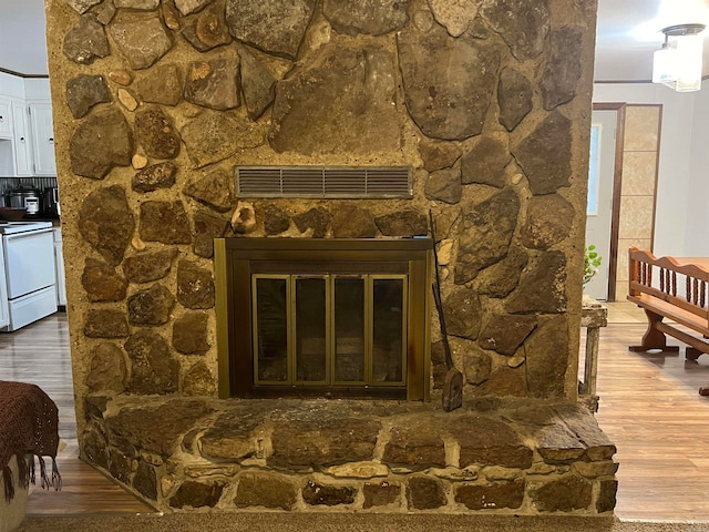 room details featuring wood-type flooring, white range oven, and a stone fireplace