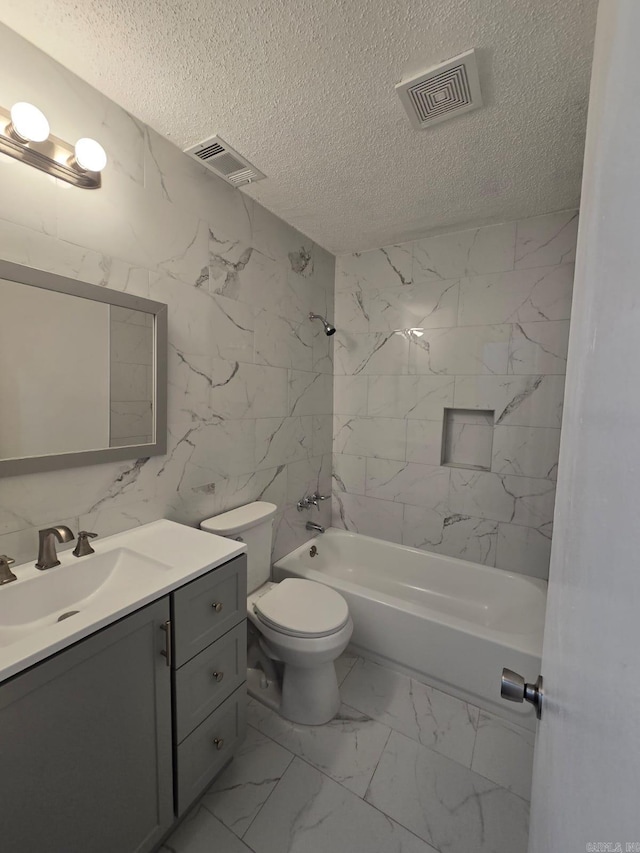 full bathroom with tiled shower / bath combo, a textured ceiling, toilet, vanity, and tile walls